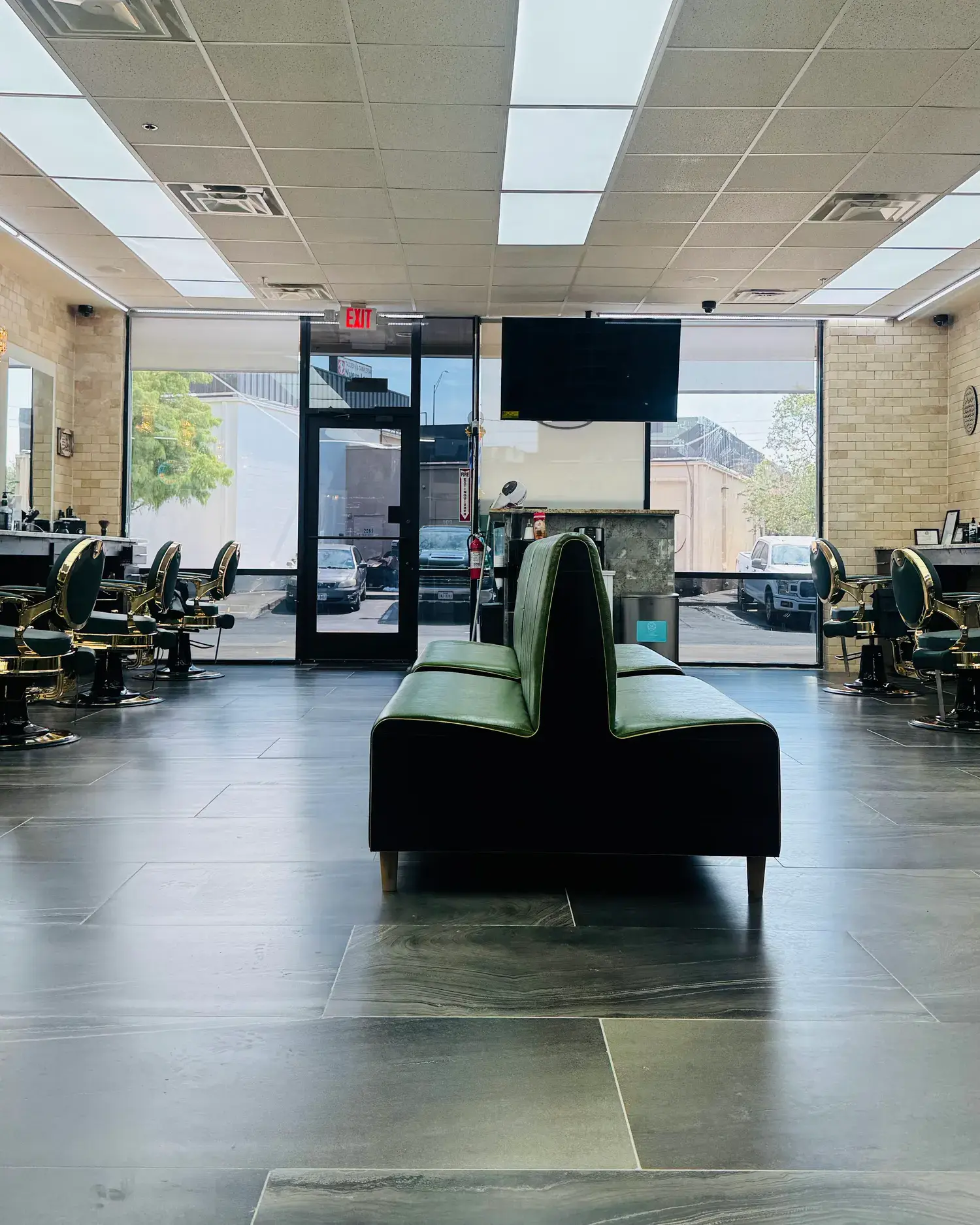 Green leather bench and brass barber chairs on the floor of KP's Barber Shop